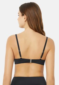 Black bra with adjustable straps and a metal clasp closure. Smooth texture, simple design, and a minimalistic style, viewed from the back.