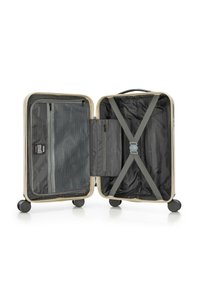 Tvrdý kufr v krémové barvě s černým interiérem. Obsahuje síťovou kapsu, zipovou přihrádku a křížové popruhy pro bezpečné uložení věcí. Čtyři kola pro snadnou mobilitu.