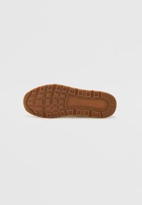 Talpă din cauciuc maro pentru sneaker, cu caneluri modelate și pătrate ridicate, având branding embossat pe mijloc. Suprafață plată, texturată.