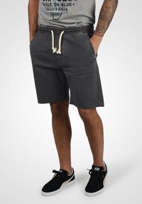 Pantalones cortos de algodón gris con cintura elástica y cordón ajustable. Cuenta con dos bolsillos laterales y un corte relajado, terminando justo por encima de la rodilla.