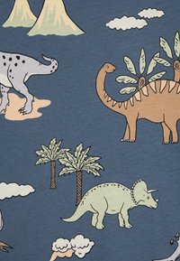 Puuvillakangas, jossa on värikkäitä dinosaurusten kuvia vihreän, ruskean ja harmaan sävyissä sinisellä taustalla, jossa on pilviä ja palmuja.