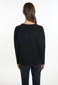 Czarny, oversized sweter z okrągłym dekoltem, opadającymi ramionami i prążkowanym wykończeniem, wykonany z miękkiego, teksturowanego materiału dzianinowego.