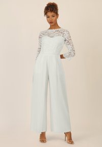 Weißer Jumpsuit mit einem Spitzen-Longsleeve-Oberteil, geraden, weiten Beinen und einer gefalteten Taille. Glattes Material mit einer taillierten Silhouette.