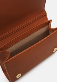 Barna bőr pénztárca sima felülettel, bézs belső résszel, több rekesszel és aranyszínű fém díszítésekkel.