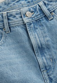 Shorts en denim bleu clair avec un motif délavé, dotés d'un bouton en métal à la taille, de coutures visibles et d'un design à cinq poches.
