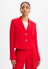 Rote taillierte Blazerjacke mit Reverskragen, zwei Vorderaschen und zwei weißen Knöpfen. Hergestellt aus glattem Stoff, mit langen Ärmeln und figurbetontem Schnitt.