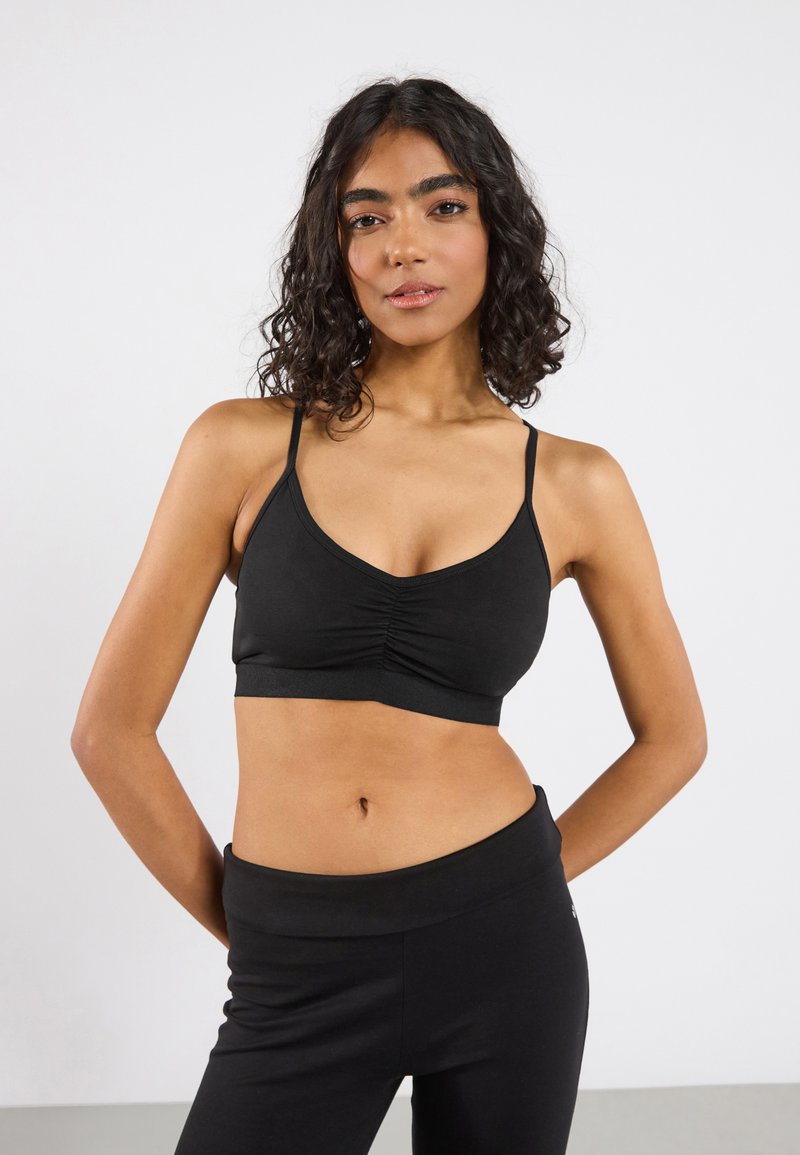 Svart bralette med justerbare stropper, dyp V-hals og rynkede detaljer foran. Glatt stoff med en tettsittende silhuett.