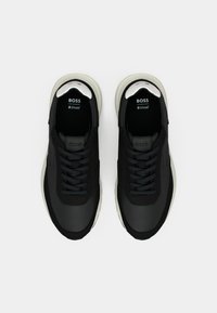 Μαύρα αθλητικά παπούτσια με λείο υφασμάτινο επάνω μέρος, κλασικό σχέδιο με κορδόνια και λευκή σόλα. Διακοσμημένα με ασημένιες λεπτομέρειες στη φτέρνα.