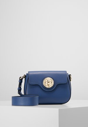 Kleine blauwe leren crossbodytas met brede riem en ronde gouden sluiting op een effen witte ondergrond en achtergrond.