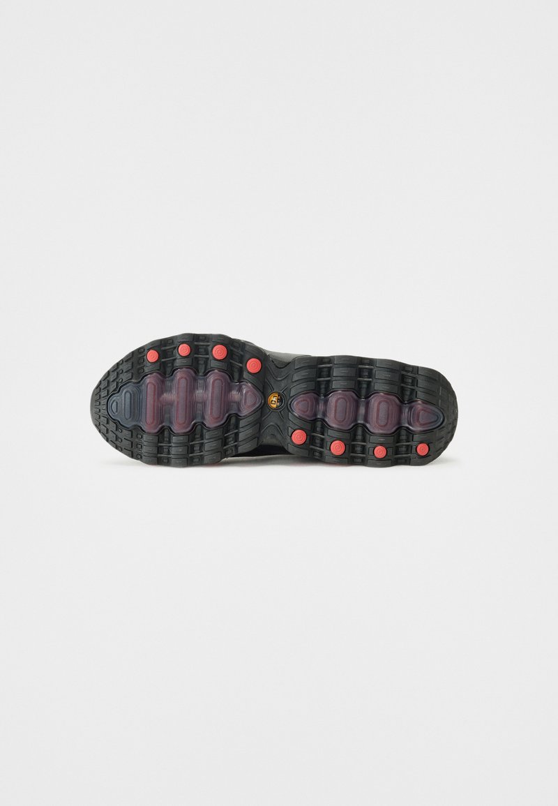 Schwarze Sport-Schuhsohle mit gummierter Textur. Verfügt über rote kreisförmige Akzente und strukturierte Rillen für besseren Halt. Klare Plastikelemente enthalten.