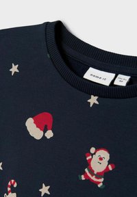 Suéter de manga larga en navy de algodón suave, con gorros de Santa rojos y figuras de Santa de dibujos animados, con estrellas beige dispersas por la tela.