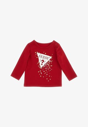 T-shirt rouge à manches longues pour tout-petit avec un logo triangle blanc portant l’inscription « GUESS U.S.A. », entouré de formes d’étoiles dorées, et des boutons-pression à l’épaule.