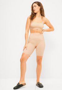 Beige naadloze crop top en korte broek tot boven de dijen, gemaakt van rekbaar materiaal, met een getailleerd ontwerp, een gladde textuur en geen zichtbare naden.