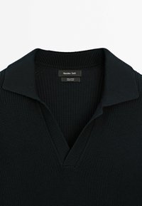 Polo en maille noire avec col côtelé et ouverture en V, étiquette Massimo Dutti, fabriqué en 100 % coton.