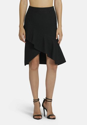 Jupe noire, longueur genoux, avec un ourlet à volants et une fente diagonale. Fabriquée dans un tissu texturé présentant de subtiles rayures verticales.