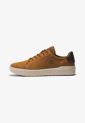 Sneaker din piele maro cu finisaj neted, cu capac pentru călcâi de un maro închis contrastant și talpă din cauciuc alb. Are vârf rotund și design clasic cu șireturi.