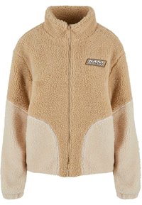 Kohvikangast zip-up jakk tan värvuses, kõrge krae, tekstuuriga kangas ja kontrastse heleda beeži külgpaneeliga, valge äärisega. KANI SPORT logo mündipatch.