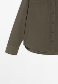Long-sleeve olive green button-up shirt with curved hem and buttoned cuffs, displayed against white background.