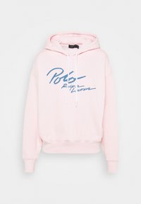 Ljusrosa hoodie med dragsko i huvan, ribbade ärmslut och en stor blå "Polo"-logotyp över framsidan. Mjuk tygkänsla.