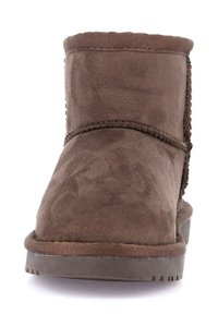 Stivale alla caviglia in suede marrone con cuciture a vista e suola in gomma piatta, mostrato frontalmente su uno sfondo bianco.