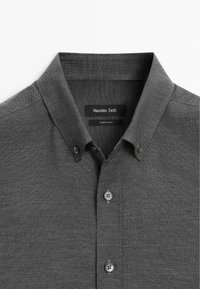 Donkergrijze shirt met een knoopsluiting kraag, geweven textuur en voorsknoopjes. Label zegt "Massimo Dutti." Eenvoudig, klassiek ontwerp.