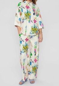 Bloemmotief shirt en broekset in crème, met levendige kleuren, oversized pasvorm, kraag en wijde pijpen. Gelaagd stof.