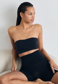 Top bandeau negru cu un bandaj lat și pantaloni scurți high-waisted asortati. Fabricat dintr-un material neted, prezintă un design minimalist și fără elemente hardware vizibile.