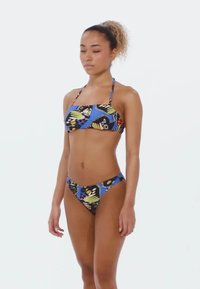 Bikini set with a blue base featuring butterfly and geometric patterns. Material appears smooth; top has thin straps; bottom is a low-rise cut.