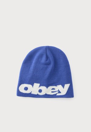 Синя плетена шапка с бял дебел малък "obey" текст отпред, показана на обикновен светъл фон.