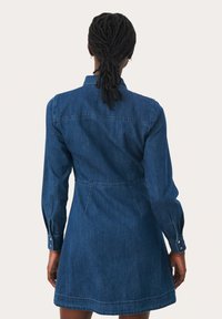 Denim dress in dark blue, featuring a fitted waist, long sleeves with buttoned cuffs, and a slightly flared skirt. Classic collar design.