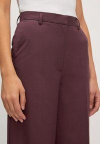 Bordeaux wijde broek gemaakt van een gladde, gestructureerde stof, met een getailleerde taille en zijzakken.