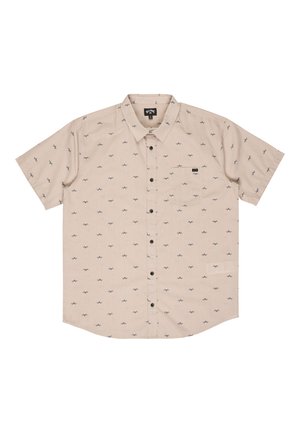 Beżowa koszula na krótki rękaw z małymi czarnymi wzorami mew i pojedynczą kieszenią na piersi po lewej stronie.
