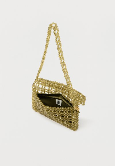 Χρυσό τσαντάκι φάκελος με ανοιχτό καπάκι, το οποίο διαθέτει λουρί με χάντρες και εσωτερικό από σκουρόχρωμο ύφασμα με μια μικρή ετικέτα εσωτερικά.