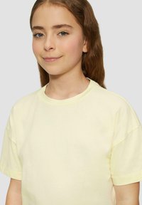 Hellgelbes Rundhals-T-Shirt mit kurzen Ärmeln, aus weichem Baumwollstoff gefertigt. Es hat eine lockere Passform und eine glatte Textur.