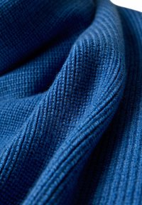 Tissu tricoté en bleu profond, présentant un motif texturé avec des côtes en relief et des zones lisses, mettant en valeur des fibres douces et fines.