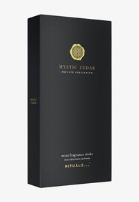 Czarny prostokątny pudełko z fakturowaną powierzchnią, złote logo i biały tekst. Zawiera miniaturowe patyczki zapachowe oznaczone jako "Mystic Cedar".