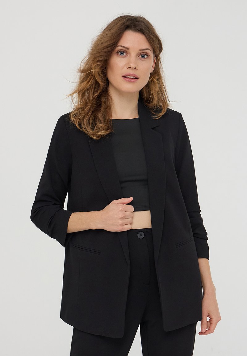 Blazer nero realizzato in tessuto liscio, con chiusura a un bottone, rever a punta e due tasche frontali. Vestibilità slim e su misura.