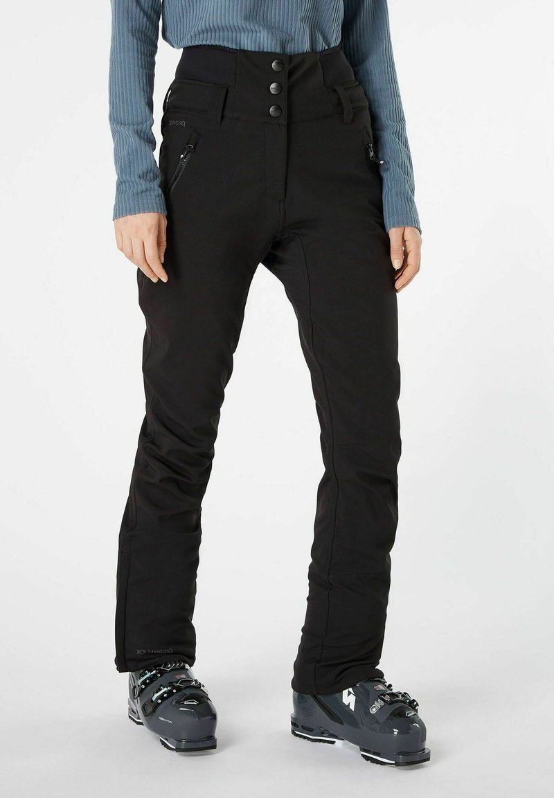 Zwarte skibroek met een hoge tailleband, voorzien van een sluiting met drie knopen, ritszakken en een tapered fit. Gekozen met grijze skibots.