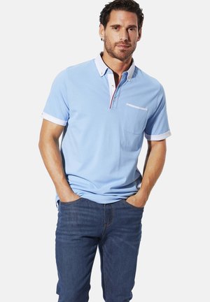 Light blue polo shirt with short sleeves, white patterned collar and cuffs, buttoned placket, and a chest pocket. Worn with dark blue jeans.
