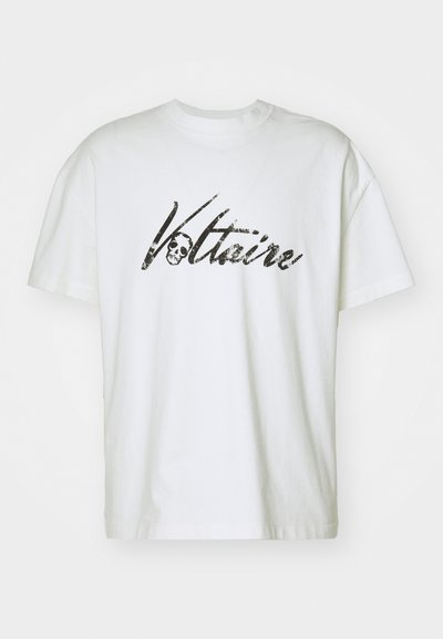 Camiseta de algodón blanca con mangas cortas y un corte holgado, que presenta una impresión gráfica negra de "Voltaire" y un diseño de calavera.