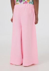 Pantaloni ampi rosa in tessuto texturizzato, con fascia elastica in vita e vestibilità morbida, caratterizzati da un orlo liscio e senza decorazioni visibili.