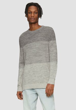 Grijze gebreide trui met een gradientontwerp, ronde halslijn, lange mouwen en een zachte textuur. Draagt over lichtblauwe jeans.