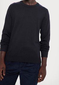 Black knitted sweater with a round neckline, featuring colorful stripes on the shoulders. Long sleeves with ribbed cuffs and hem.