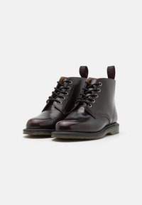 Burgunderfarbene Lederstiefeletten mit schwarzen Schnürsenkeln, runder Spitze, kontrastierenden Nähten, Ziehschlaufen und einer strukturierten Gummisohle.