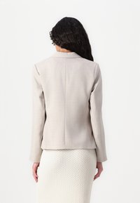 Sacou elegant de color gri deschis, cu rever tăiat, umeri structurați și mâneci lungi. Material texturat cu un finisaj neted.