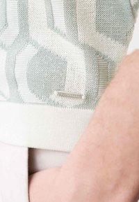 Sweter z dzianiny w jasnym zielonym i białym kolorze w geometryczne wzory. Posiada srebrną metkę z napisem "AUTOGRAPH" na dółach. Miękka tekstura.