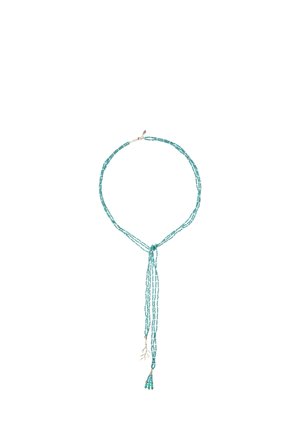 Collier de perles turquoise à plusieurs rangs, avec un détail en nœud et un pendentif pompon. Les rangs varient en longueur pour un effet cascade.