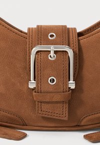 Brown leather bag featuring a prominent silver buckle, textured surface, and stitching details, with an adjustable strap for closure.