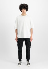 Witte, oversized T-shirt met korte mouwen en een ronde hals, gecombineerd met zwarte cargobroeken met zijzakken en elastische manchetten.