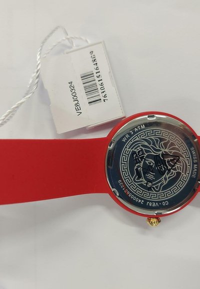 Red silicone watch with a circular case. Back features a Greek-style pattern and a face design. Includes a price tag with barcode.
